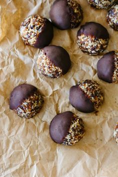 chocolate covered donuts with sprinkles and nuts on parchment paper lined up