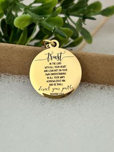 a gold plated necklace with the words trust and an image of a plant behind it