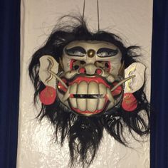 a mask hanging on the wall with long hair