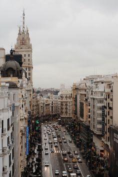 a city street filled with lots of traffic next to tall buildings and tall spires