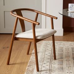 a chair sitting on top of a wooden floor next to a glass table with a cup