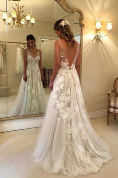 a woman standing in front of a mirror wearing a wedding dress with flowers on it