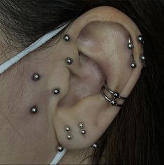 a woman with piercings on her ear and behind the ear is a pair of silver balls