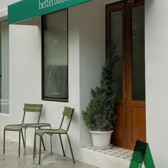 two green chairs sitting in front of a building