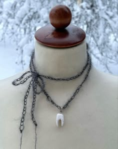 a mannequin wearing a necklace with an elephant's tooth pendant on it