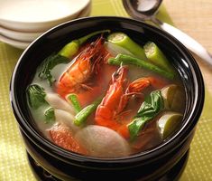 a bowl of soup with shrimp, carrots and celery on the side