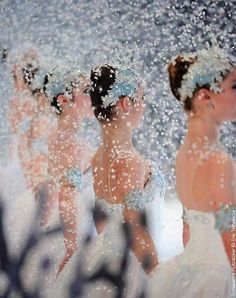 three women in white dresses are looking at each other through a mirror with water droplets all over them