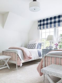 a bedroom with white walls and pink bedspreads, plaid curtains, and checkered window coverings