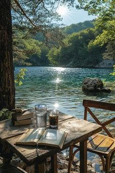 an outdoor table and chairs next to a body of water with trees in the background