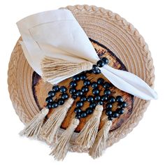 a plate topped with tassels and black beads next to a napkin on top of it