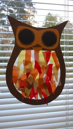 an owl made out of construction paper sitting on top of a window sill next to blinds