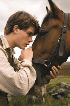 a man standing next to a brown horse