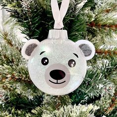 an ornament shaped like a bear hanging from a christmas tree with snow on it