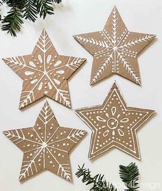 four paper snowflakes are hanging on the wall next to some pine branches