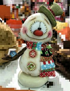 a snowman with a green hat and scarf around it's neck, standing on a table