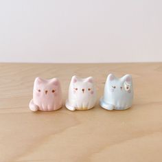 three ceramic cats sitting on top of a wooden table