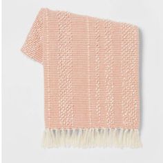 an orange and white knitted blanket with fringes on the bottom, in front of a