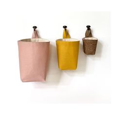 three storage bins are hanging on the wall next to each other in different colors