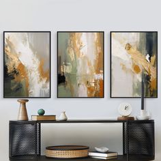 three paintings hang on the wall above a table