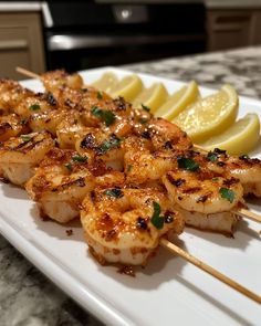 shrimp skewers with lemon wedges on a white plate