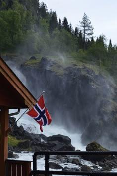 a flag flying in front of a waterfall