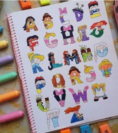 an open notebook with letters and numbers drawn on it next to colored crayons