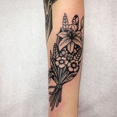 a black and white flower tattoo on the right arm, with an arrow in the center