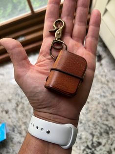 a hand holding a brown leather case with a pair of scissors on it's wrist