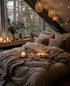 an unmade bed with candles on it in front of a window and some windowsills