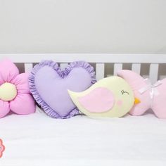 three stuffed animals sitting on top of a white crib next to a pink flower