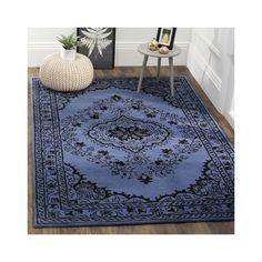 a blue area rug with an ornate design on the center and bottom, in front of a white wall