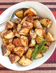 a white bowl filled with cooked potatoes on top of a red and white checkered table cloth