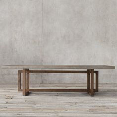 a wooden table sitting on top of a hard wood floor next to a cement wall