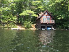 a house on the water with a boat in front of it and some trees around