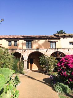 an old building with arches and flowers in the foreground, on a sunny day