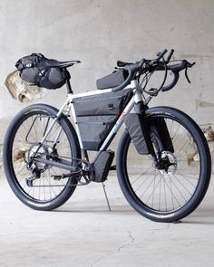 a bicycle parked in front of a wall with a backpack on it's back