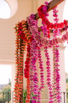 the flowers are hanging down from the ceiling in the building's balcony area, which is decorated with pink and red orchids