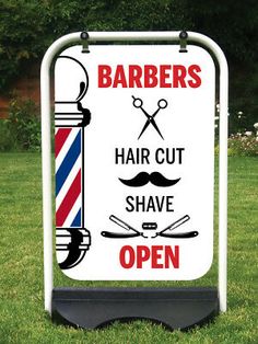 a barbers sign on the grass with scissors and haircuts in front of it