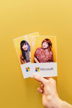 someone holding up two photos of themselves on a yellow background with the microsoft logo in front of them