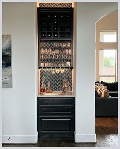 a living room filled with furniture next to a wall mounted wine rack in front of a couch