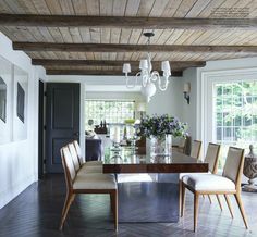 a dining room table with chairs and a chandelier hanging from it's ceiling