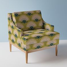 an upholstered chair with green and blue designs on the back, against a light blue background