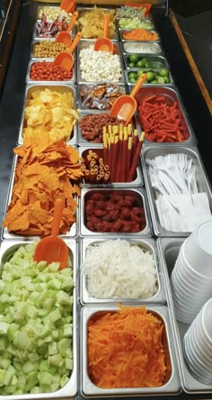 many different types of food are in trays on the buffet table with utensils