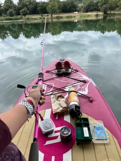 a person on a pink boat with fishing rods and other things in the water behind them