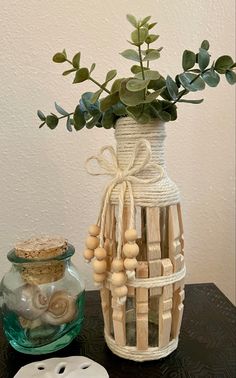 a vase filled with green leaves and beads next to a cookie jar on a table