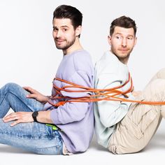 two men sitting on the ground with ropes tied to their backs and hands behind them