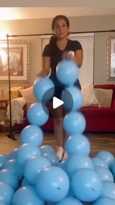 a woman standing on top of a pile of blue balloons