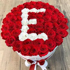 a large bouquet of red and white roses in the shape of the letter b on a wooden table