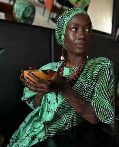 a woman wearing a green dress and holding a bowl with food in it's hands