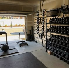 there is a gym room with exercise equipment in the corner and an open garage door